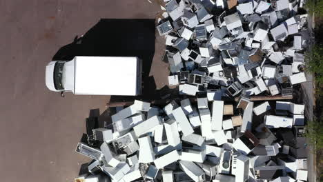 truck drives away after disposing of broken appliances at landfill, top view