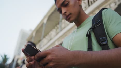 primer plano de un hombre de raza mixta usando un teléfono inteligente en la calle