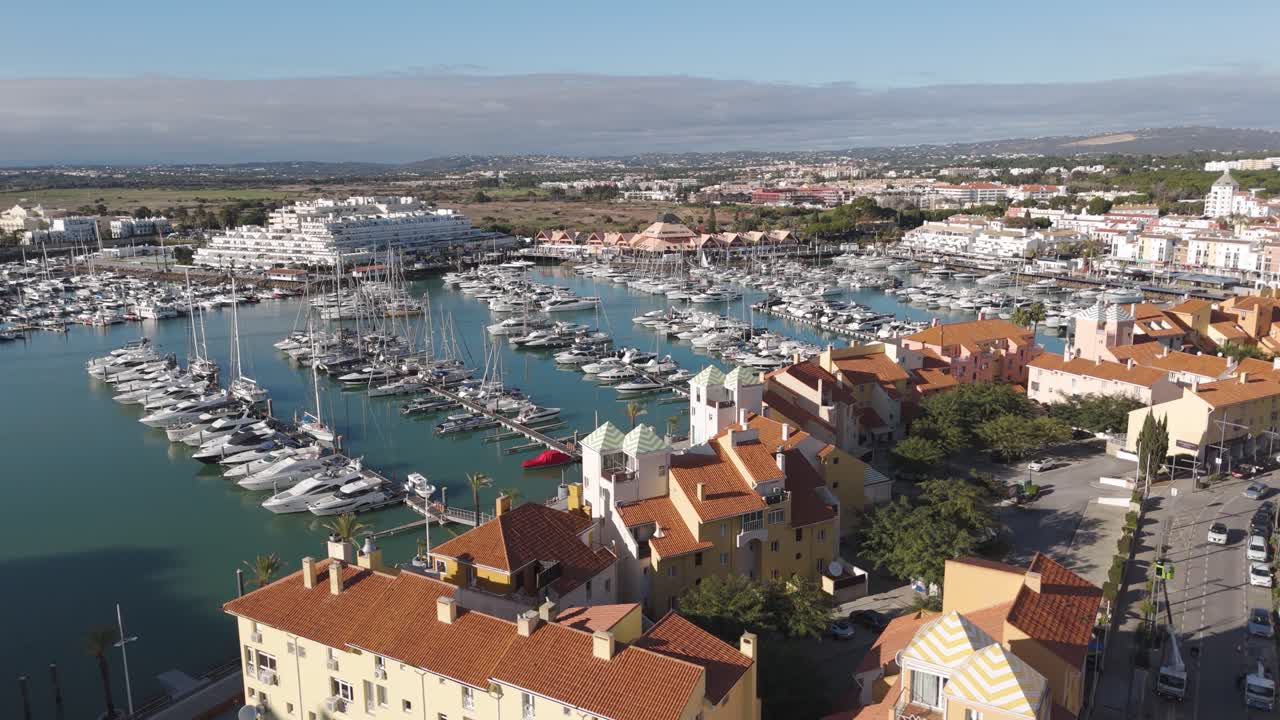 Vista aerea fluida che cattura la disposizione del porto turistico insieme all'architettura costiera adiacente a Vilamoura.