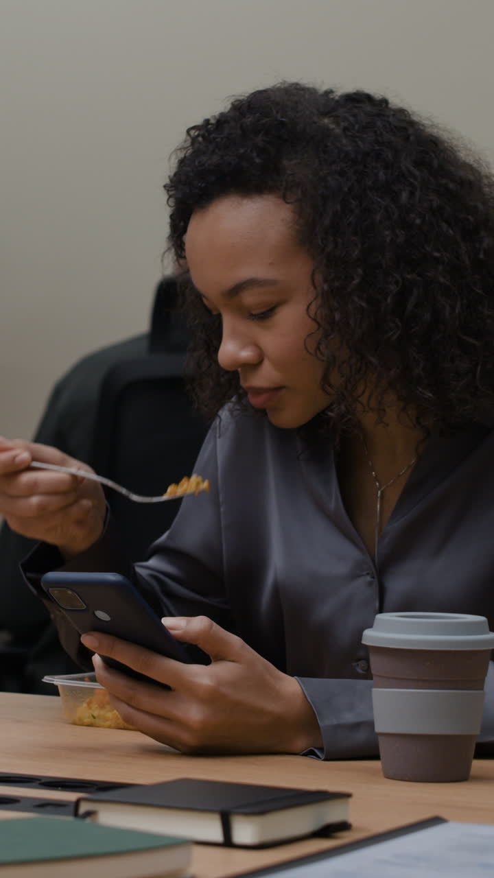 Woman Eating Lunch While Using Phone at Office Desk