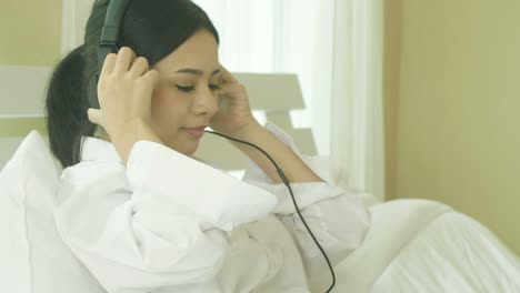 young asian women listening music on bed.