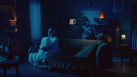 night scene with a woman on a couch and various figures appearing behind her