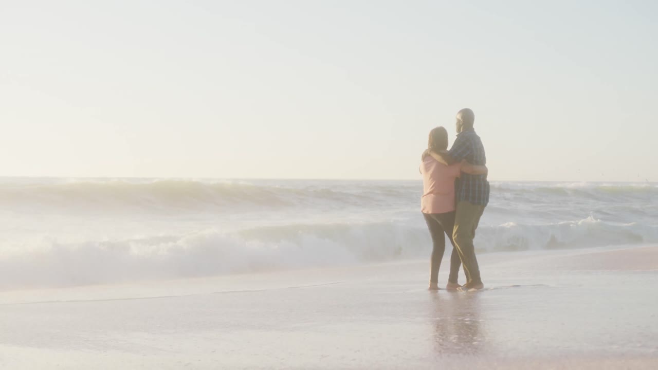 웃고 있는 아프리카계 미국인 부부가 손을 잡고  ⁇ 은 해변에서 춤을 추고 있습니다.