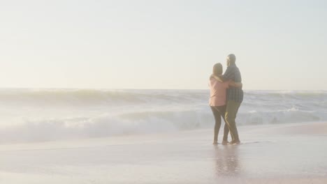 una pareja afroamericana de alto nivel sonriendo tomados de la mano y bailando en una playa soleada