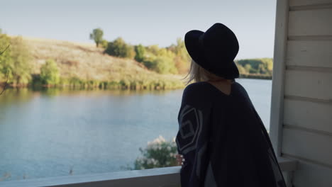 portrait of a stylish woman in a hat and poncho on a veranda 2