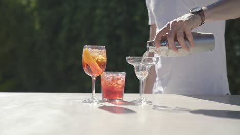 bartender wearing white t-shirt preparing tasty cocktail in outdoor space in slow motion