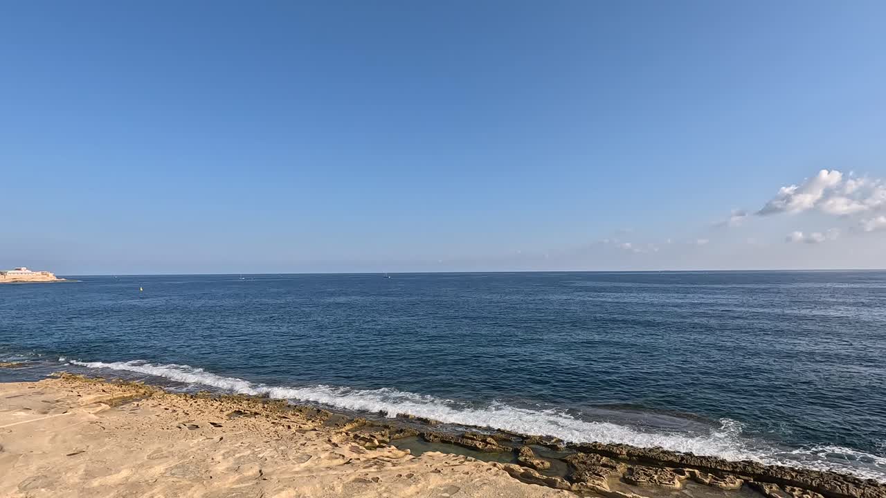 몰타의 해안선 근처의 길을 따라 걸어서 바다 지평선을 내려다보고 있습니다.