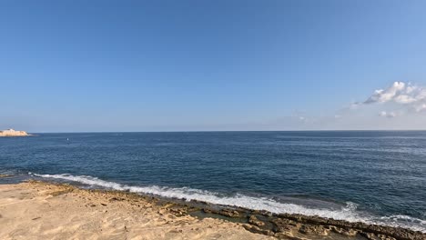 Walking-along-the-path-near-the-coastline-of-Malta,-overlooking-the-sea-horizon