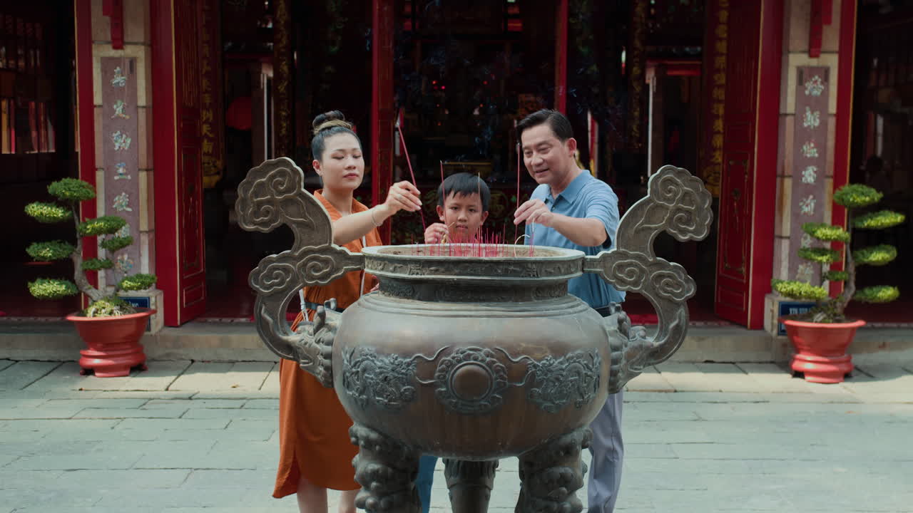 Family Performing Ritual with Burning Candles near Temple