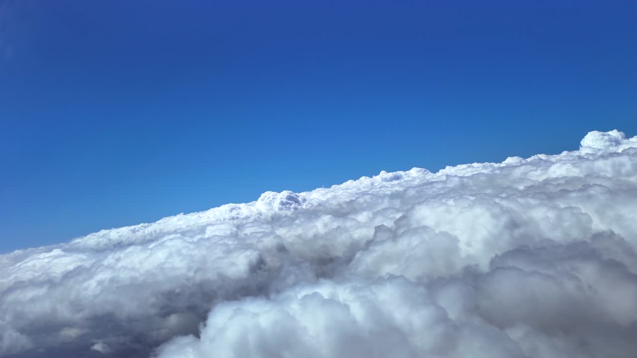 A Pilot’s view from cockpit doing. a right turn over an endless sea of clouds under a deep blue sky