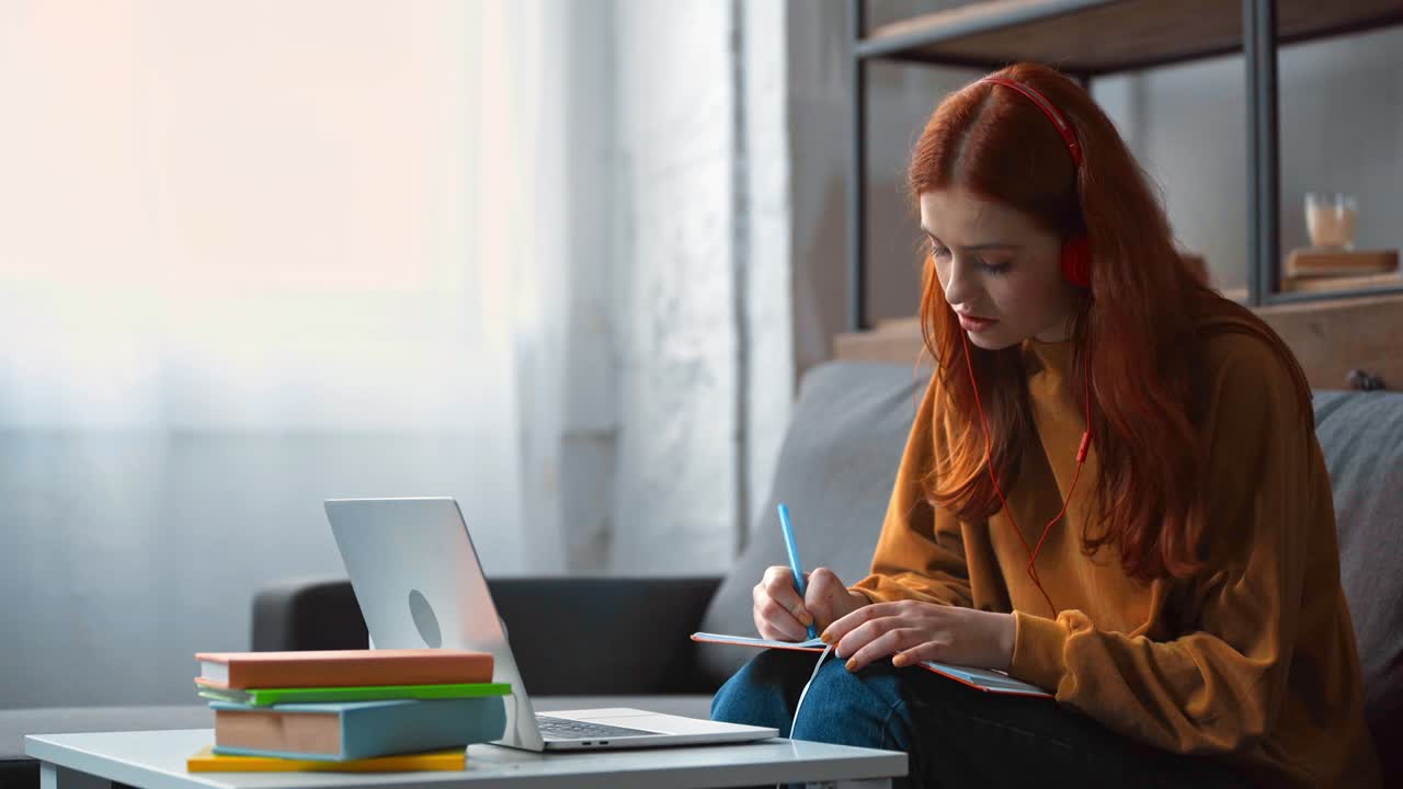 positive teenage girl in headphones doing homework