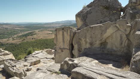 Panorámica-De-Izquierda-A-Derecha-Del-Cuadro,-Que-Muestra-Las-Estructuras-Rocosas-De-La-Antigua-Ciudad-De-Perperikon-Y-El-Valle-Que-Se-Encuentra-Debajo-En-La-Provincia-De-Kardzhali-En-Bulgaria