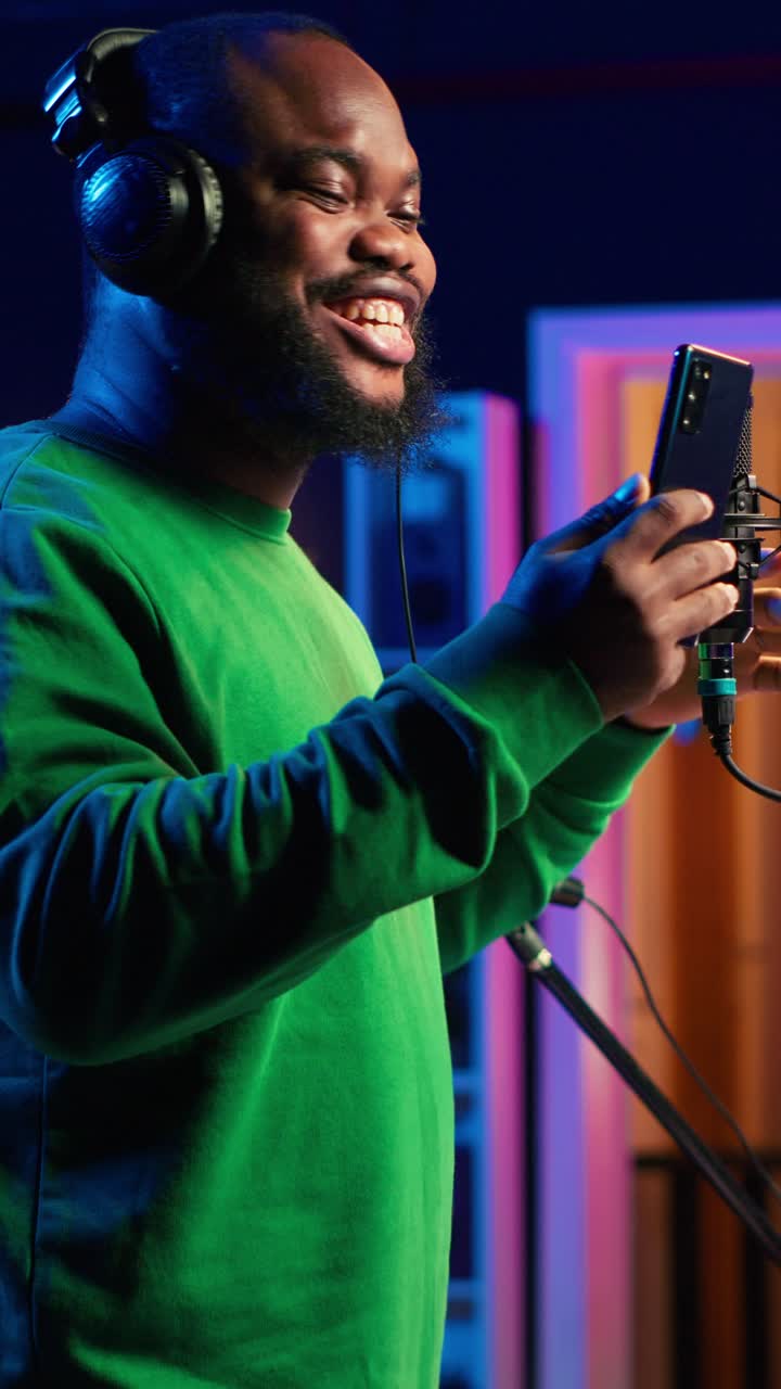 Glad afroamerikansk mann som synger i mikrofon i et innspillingsstudio