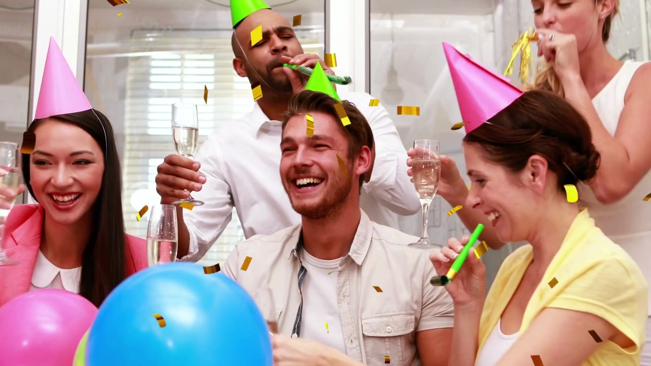 Colleghi che alzano i calici, facendo volare coriandoli dorati e soffiando trombette da festa durante una celebrazione in ufficio
