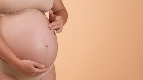 pregnant woman applying cream to her belly