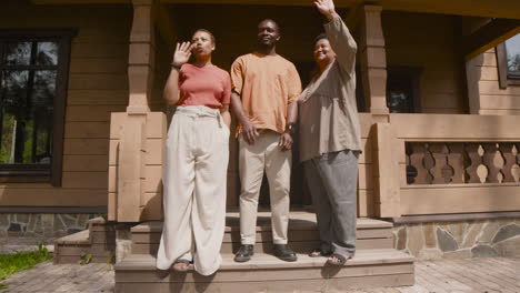 family waving hands standing outside home in a sunny morning