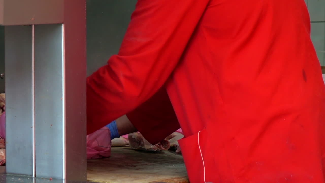A man in gloves wraps fresh, juicy beef meat into the plastic bag for a customer in the Market of Paris, France