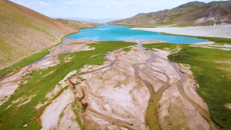 aerial view of arashan lake with calm blue waters on foothill of mountains in uzbekistan