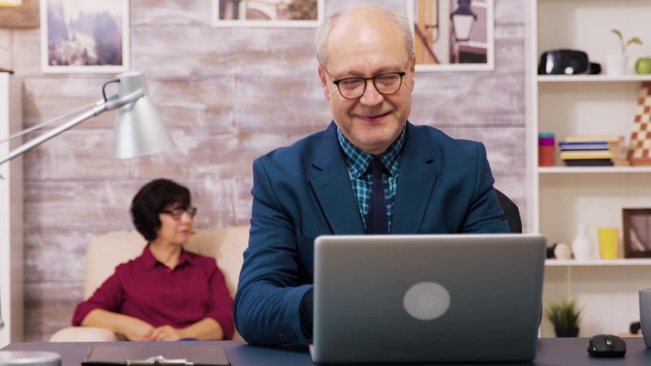 Senior Businessman Sitting at Desk and Opening Laptop in Home Office