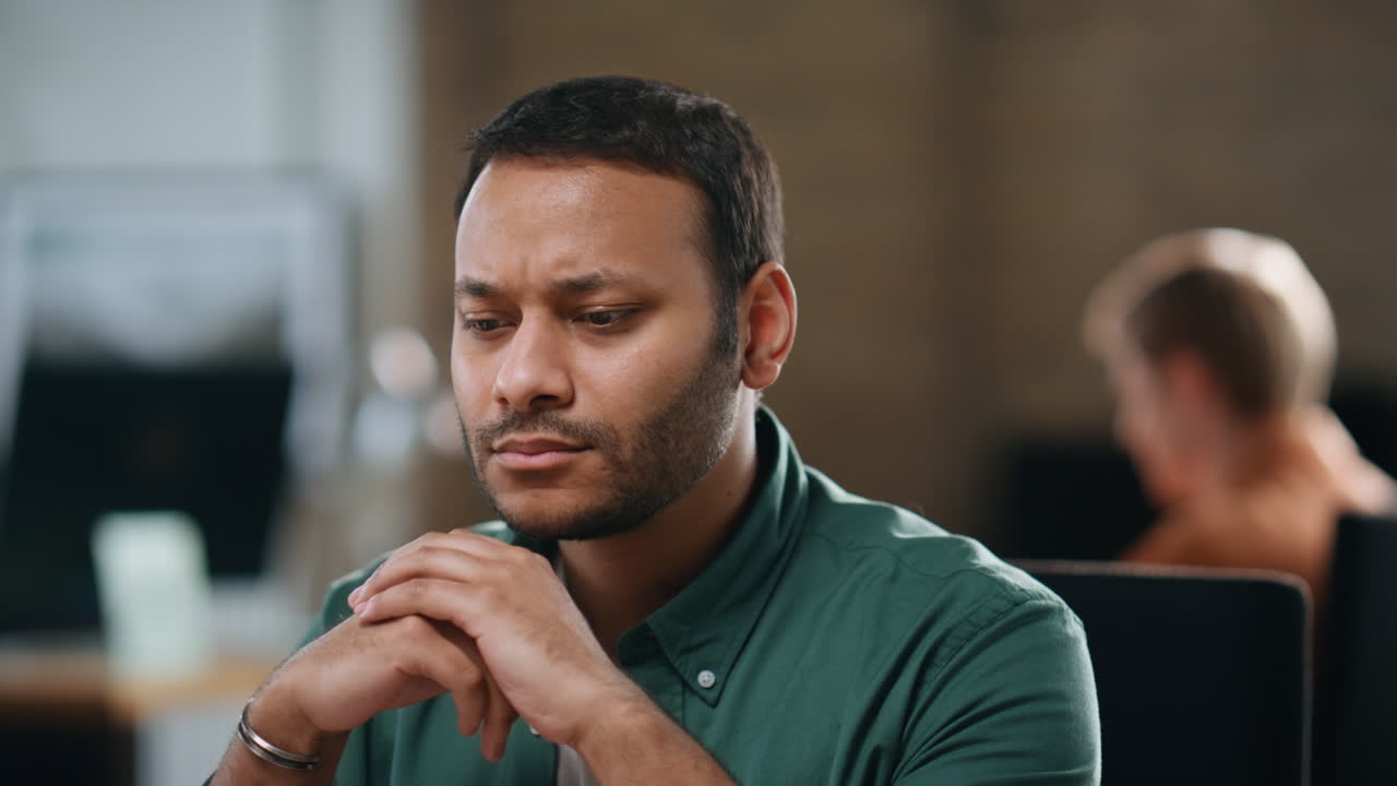 Frowning man sitting office thinking at work close up. Thoughtful businessman