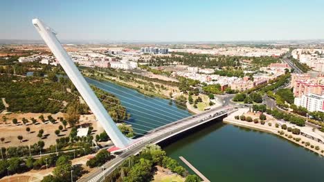 a striking aerial view of a modern suspension bridge by santiago calatrava spanning the guadalquivir river in sevilla, spain, surrounded by lush parks, residential buildings, and scenic landscapes