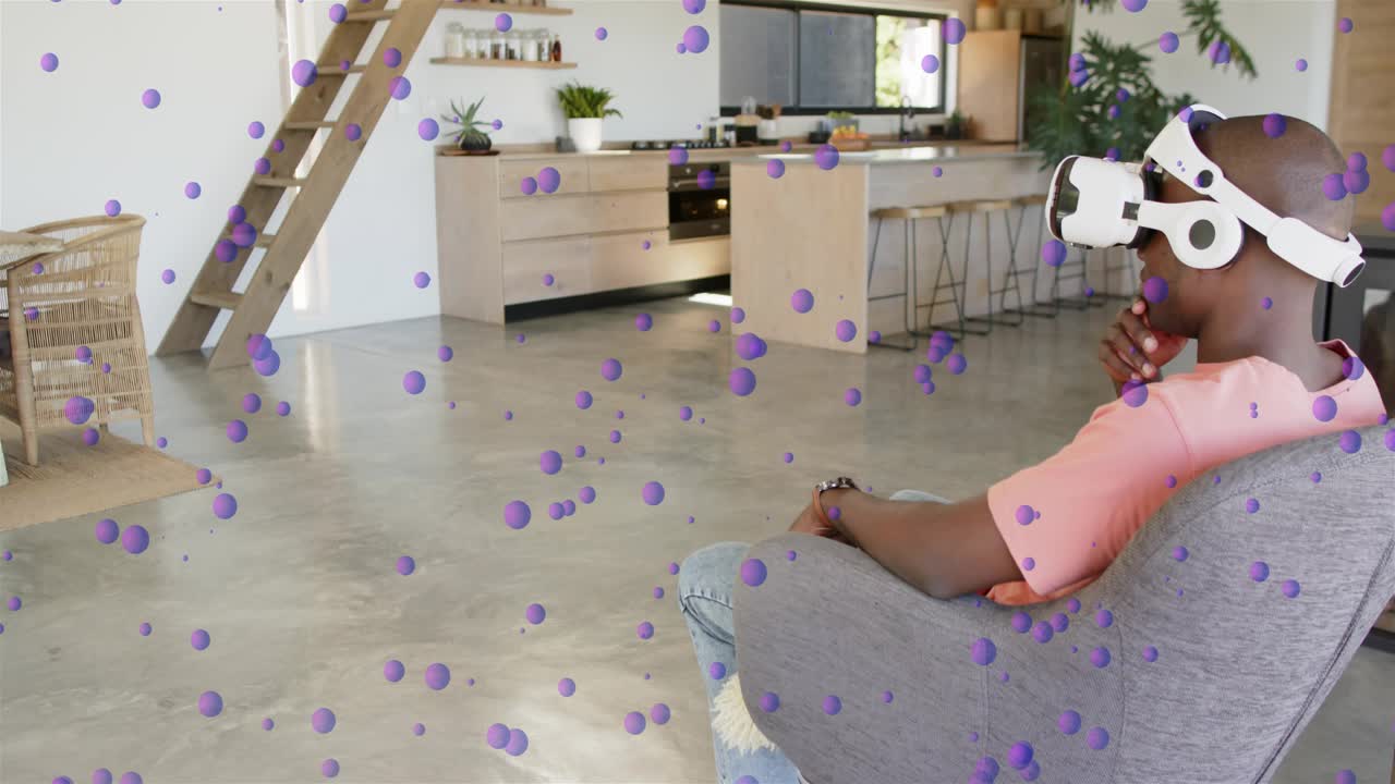 Man wearing VR headset raising right hand, pointing and selecting purple spheres in technology demo