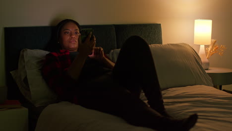 woman using phone in bed at night