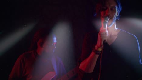male singer and guitarist performing on live music stage, showing animated sound waves floating