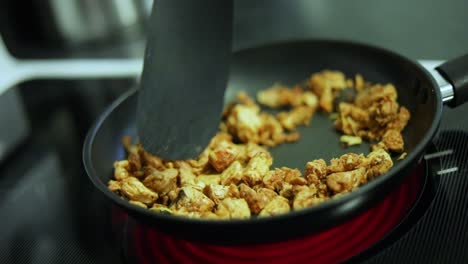 Toma-En-Cámara-Lenta-De-Alguien-Cocinando-Pollo-Chisporroteante-En-Una-Sartén-Sobre-Una-Estufa