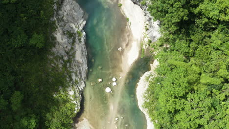 Bird's-Eye-View-Over-Nizao-River-Surrounded-With-Lush-Vegetation-In-Dominican-Republic---drone-shot