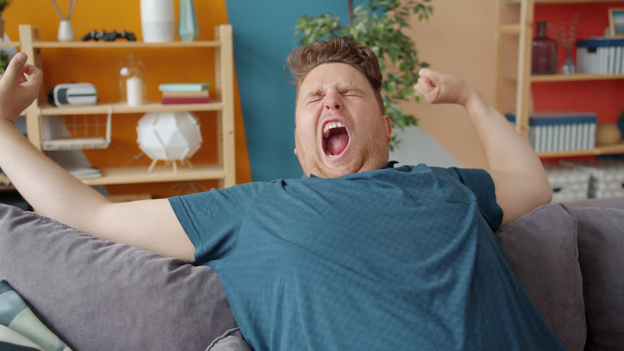 Man Yawning and Stretching on a Couch