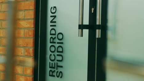 a woman in a brown skirt enters the door of a recording studio