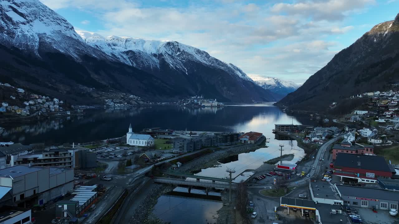 Aerial over Odda Norway at dawn, flying along River Opo towards Sorfjorden. Snow capped mountains and fading daylight