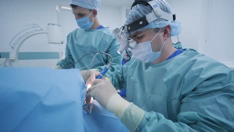 operation of removing tonsils under deep anesthesia, surgeon uses latest devices, cold plasma method, cuts swelling in throat, doctor works with new probe, medical headlamp, surgical loupes