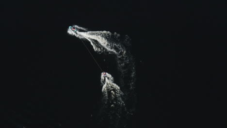 aerial view of a ringo ride behind a jetski in deep dark water in a river in sweden