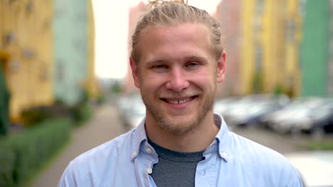 portrait of a young man smiling and looking at camera outdoors