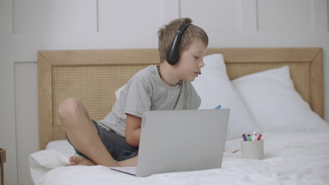 portrait of little boy with headphones at home child is drawing at copybook and listening to music