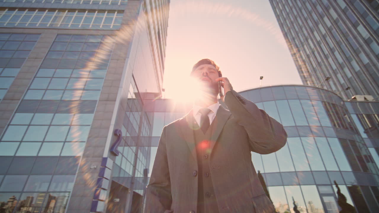 부유한 남자가 거리의 빛에서 드폰으로 이야기하고 있습니다. 매니저는 전화로 컨설팅합니다.