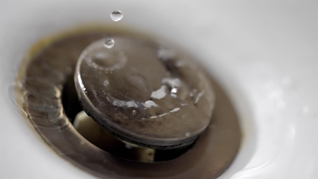 Water Dripping into Bathroom Sink Drain Close Up