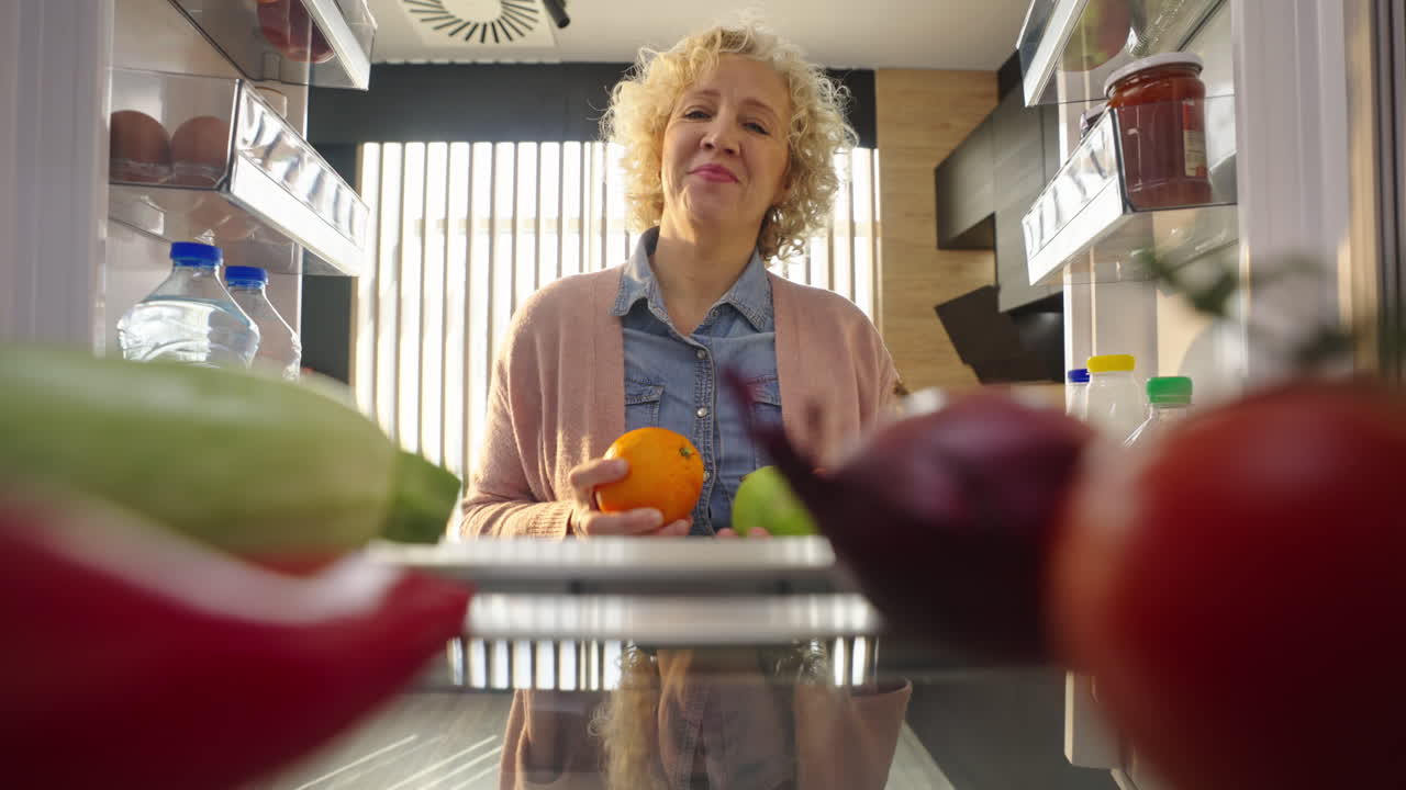 Donna che prende frutta dal frigorifero