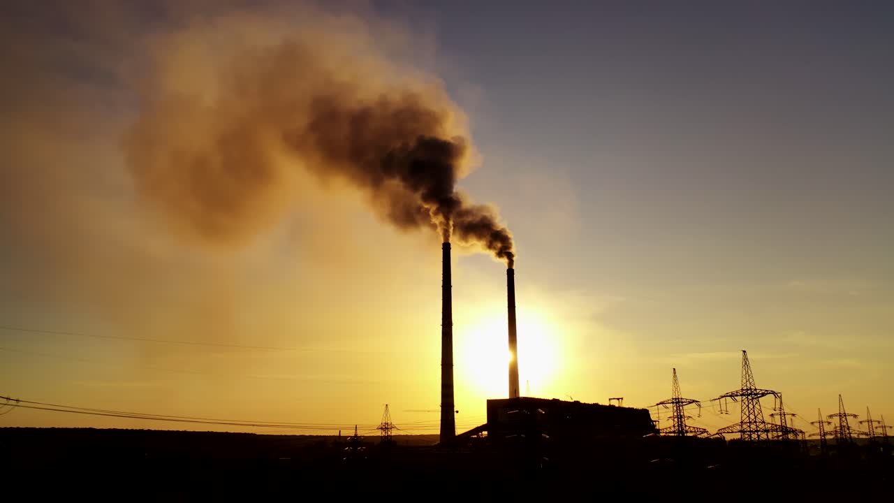 Black factory background. Metallurgical plant with two pipes in the evening. Dirty emissions pouring out of pipes at sunset.