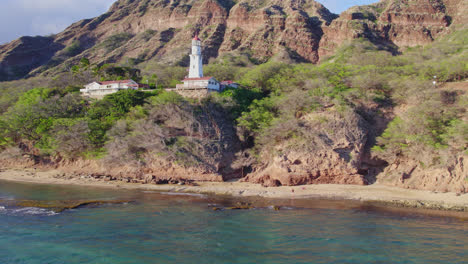 drone-footage-of-Diamond-Head-lighthouse-on-Oahu-Hawaii-with-Diamond-Head-volcanic-mountain-formation-behind-it-on-the-island