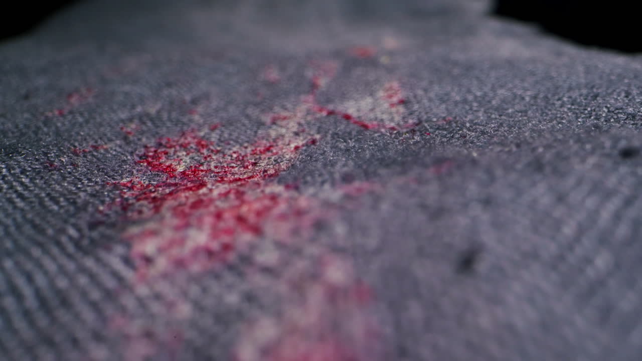 Closeup view of reddish stains on dark denim fabric, beautifully showcasing the intricate texture and color contrast