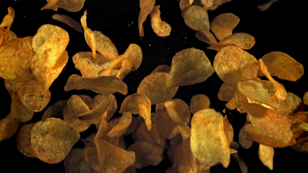 Crispy Golden Potato Chips Falling in Slow Motion on Black Background