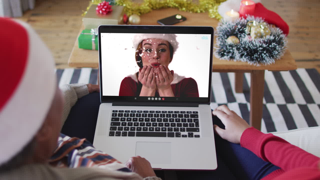 African american mother and daughter using laptop for christmas video call with woman on screen