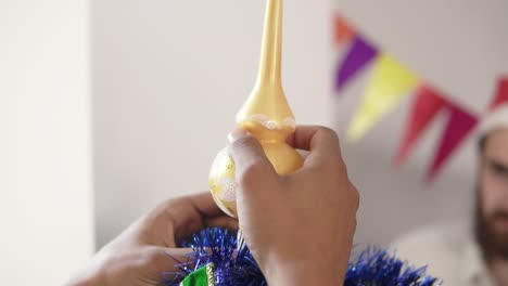 close up view of and african american hand putting a decoration on the top of the little artificial christmas tree decorated by