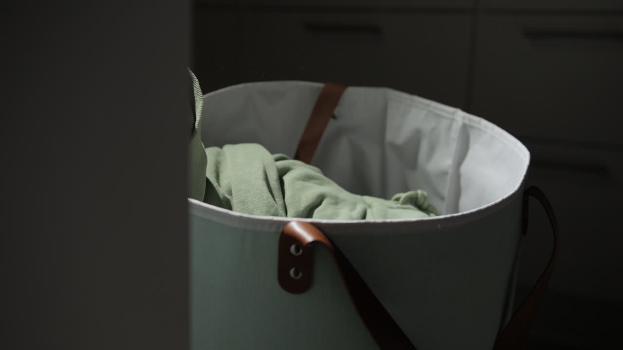 Low angle closeup of dirty clothes dropping into laundry basket