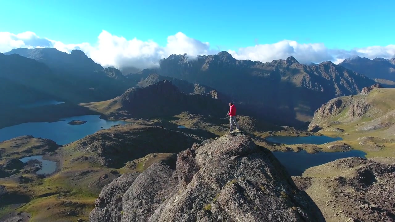 Fotografo su vetta alpina che domina laghi di montagna