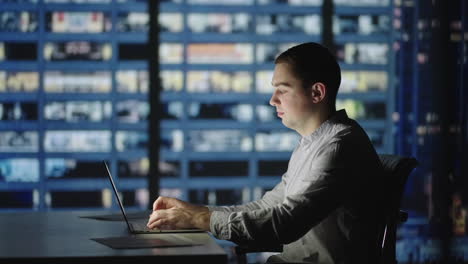 Geschäftsmann-Kehrt-Ins-Büro-Zurück,-öffnet-Den-Laptopdeckel-Und-Setzt-Seine-Abendarbeit-Fort.-Hübscher-Kaukasischer-Mann-Vor-Nächtlicher-Stadtszene-Im-Hintergrund.