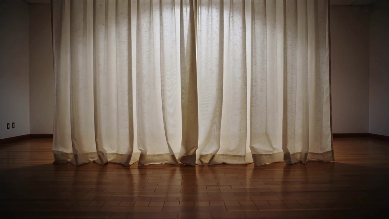 Voilages beiges ondoyant sous le flux d'air d'une ventilation, aux plis changeants et laissant passer la lumière en studio.